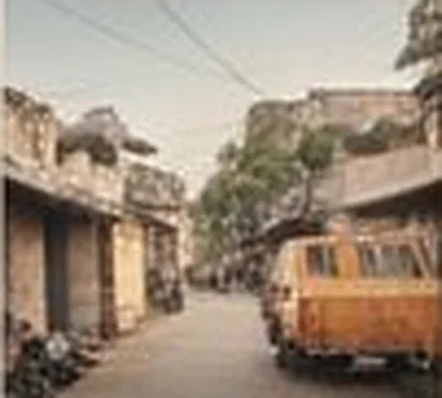 Narrow residential street with an auto rickshaw parked by old houses