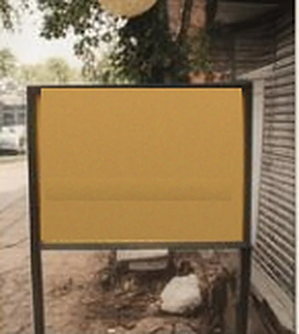 Blank signboard on a pole beside a shuttered shop